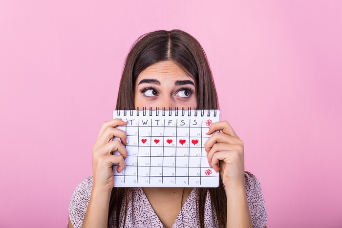 Ilustrasi menstruasi Torso of an unrecognizable woman is showing red square card to camera representing with menstruation written in white.