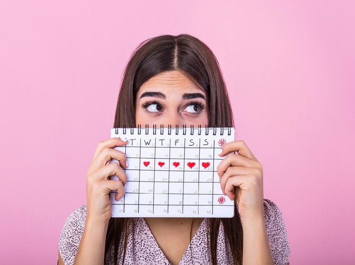 Ilustrasi menstruasi Torso of an unrecognizable woman is showing red square card to camera representing with menstruation written in white.