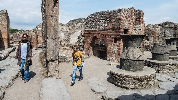 Wisatawan berjalan di situs sejarah kota Pompeii, Italia. Pompeii adalah sebuah kota zaman Romawi kuno yang telah menjadi puing dekat kota Napoli dan sekarang berada di wilayah Campania, Italia. Getty Images/Giorgio Cosulich  