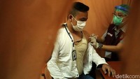 Vaksinator menyuntikkan vaksin COVID-19 di lengan kiri pedagang. Mereka melakukan penyuntikan dengan dosis yang telah ditentukan.