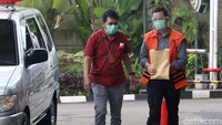 Dengan membawa map coklat, Juliari keluar dari mobil menuju gedung KPK. 