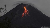 Gunung Merapi dengan awan lentikular (awan topi) di bagian atas mengeluarkan lava pijar terlihat dari Turi, Sleman, Yogyakarta.