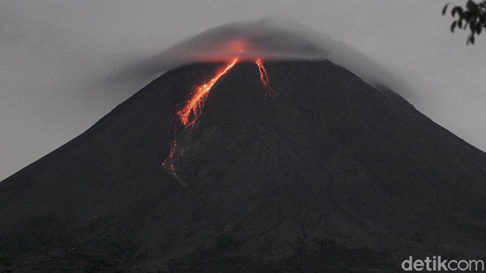 Gunung Merapi dengan awan lentikular (awan topi) di bagian atas mengeluarkan lava pijar terlihat dari Turi, Sleman, Yogyakarta, Jumat (5/3/2021). Berdasarkan pengamatan BPPTKG, pada pukul 18.00 tanggal 4 Maret 2021 hingga pukul 06.00 tanggal 5 Maret 2021. Gunung Merapi mengeluarkan lava pijar sebanyak 81 kali, dengan jarak luncur maksimal 1.200 meter ke arah barat daya.