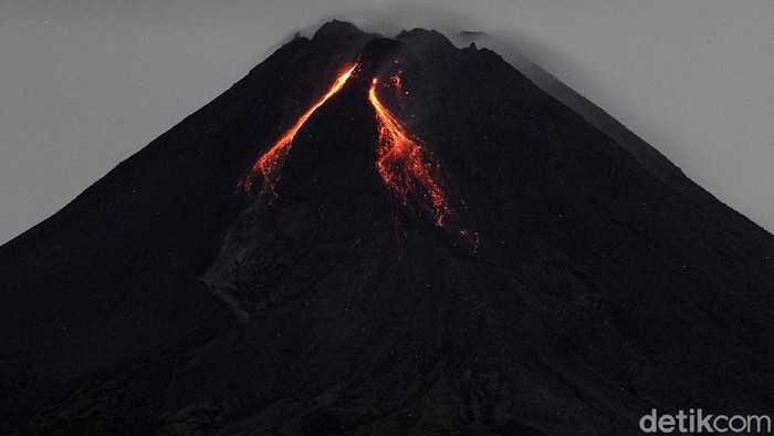 Gunung Merapi dengan awan lentikular (awan topi) di bagian atas mengeluarkan lava pijar terlihat dari Turi, Sleman, Yogyakarta, Jumat (5/3/2021). Berdasarkan pengamatan BPPTKG, pada pukul 18.00 tanggal 4 Maret 2021 hingga pukul 06.00 tanggal 5 Maret 2021. Gunung Merapi mengeluarkan lava pijar sebanyak 81 kali, dengan jarak luncur maksimal 1.200 meter ke arah barat daya.