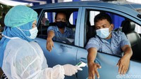 Petugas vaksinator mengecek suhu tubuh pengemudi taksi yang akan divaksinasi. Pengecekan dilakukan di dalam taksi.