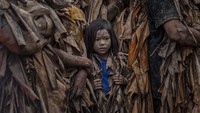 Seorang anak perempuan mengikuti Festival Taong Putik atau festival orang berlumpur di Aliaga, Filipina. Getty Images/Ezra Acayan