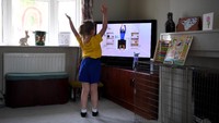 Seorang anak perempuan ikut kelas olahraga daring di rumahnya. Getty Images/Gareth Copley