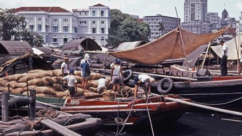 Tampak beberapa pekerja kasar menurunkan barang dari perahu. Singapura pada masa itu sempat bergabung dengan Federasi Malaysia. Foto: Vintag