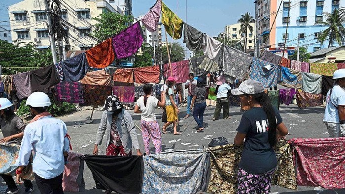 (FILES) In this file photo taken on March 3, 2021, protesters make a barricade across a road with longyi, a traditional clothing widely worn in Myanmar, during a demonstration against the military coup in Yangon. - Long sarong-like cloths strung out on lines may seem innocuous, but long-held superstitions about womens clothes has appeared to stop security forces in their tracks as they move to quell an uprising against Myanmars junta. (Photo by STR / AFP)