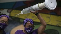 Digelar di masa pandemi, salah satu isu yang diangkat para wanita di Brasil saat Peringatan Hari Perempuan Sedunia itu adalah ketersediaan vaksin untuk semua orang. Menggelar aksi di kawasan Rio de Janeiro, para wanita yang ikut serta dalam aksi tersebut tampak membawa replika alat suntik serta menggunakan masker guna mencegah penyebaran virus Corona. AP Photo/Bruna Prado.
