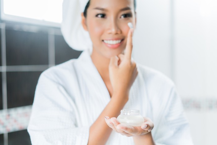 910314262 Asian women are applying cream and lotion to her face after bathing in the bathroom.