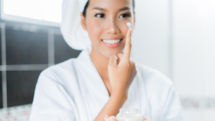 Asian women are applying cream and lotion to her face after bathing in the bathroom.