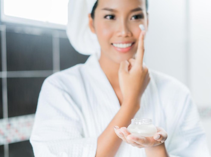 910314262 Asian women are applying cream and lotion to her face after bathing in the bathroom.