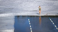 Seorang wanita bersiap berlaga di kompetisi renang musim dingin di sebuah danau dekat Vilnius, Lithuania.  