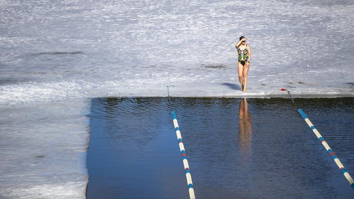 Aksi Balap Renang Dalam Es di Lithuania A woman celebrates after the finish during a winter swimming competition in the 25 meters long ice hole in a lake near Vilnius, Lithuania, Saturday, March 6, 2021. The water temperature was 3 degrees Celsius (37.4 degrees Fahrenheit), the air was -3 degrees Celsius (26,6 degrees Fahrenheit). (AP Photo/Mindaugas Kulbis)