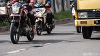 Pesepeda motor melambatkan lajunya untuk menghindari lubang. (Andhika Prasetia/detikcom)