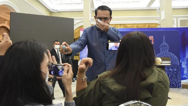 Perdana Menteri Thailand Prayuth Chan-ocha menyemprotkan alkohol disinfektan ke barisan depan wartawan yang duduk di dalam ruang konferensi pers di Government House di Bangkok, Thailand, Selasa, 9 Maret 2021.(AP Photo)
