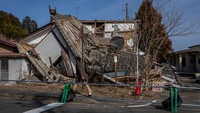 Seorang warga melintas di depan bangunan rumah yang porak-poranda usai diguncang gempa dahsyat pada 2011 silam di kawasan Futaba, Jepang, Selasa (9/3) waktu setempat.