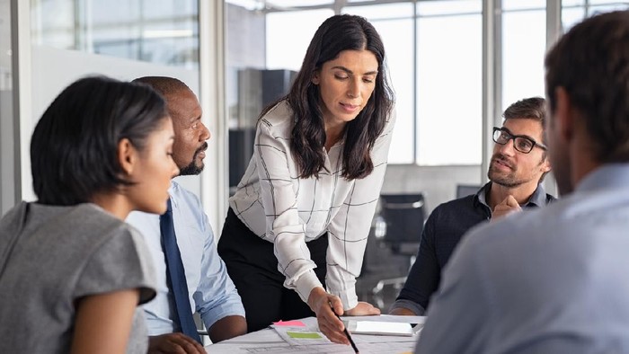 Team of multiethnic architects working on construction plans in meeting room. Engineers and designers discussing project in office. Businesswoman with business team in conference room working on blueprint.