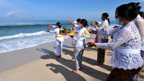 Pemuka agama Hindu memercikkan air suci saat upacara Melasti menjelang Hari Raya Nyepi Tahun Saka 1943 di Pantai Kuta, Bali, Kamis (11/3/2021). Ritual Melasti untuk menyucikan alam agar Hari Raya Nyepi dapat berjalan hening serta damai tersebut dilakukan oleh perwakilan desa adat dengan jumlah terbatas serta menerapkan protokol kesehatan untuk mencegah penyebaran pandemi COVID-19. ANTARA FOTO/Fikri Yusuf/aww.