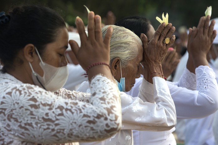 Balinese dip their feet in the sea during the ritual of Melasti in Bali, Indonesia, Thursday, March 11, 2021. The ritual, which is performed ahead of the Balinese Hindus Day of Silence, is held to purify the universe from bad influences, bad deeds and bad thoughts. (AP Photo/Firdia Lisnawati)