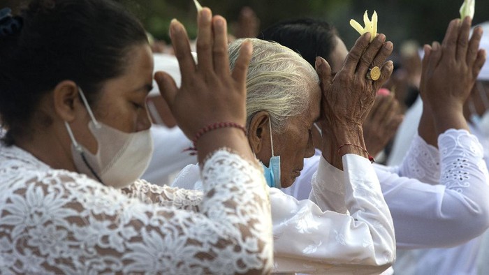 Balinese dip their feet in the sea during the ritual of Melasti in Bali, Indonesia, Thursday, March 11, 2021. The ritual, which is performed ahead of the Balinese Hindus Day of Silence, is held to purify the universe from bad influences, bad deeds and bad thoughts. (AP Photo/Firdia Lisnawati)