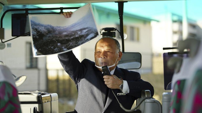 Menenang Satu Dekade, Ada Wisata Keliling Lokasi Tsunami Jepang Fumio Ito, head of public relations at Minami Sanriku Hotel Kanyo, tells his experience of 2011 tsunami disaster in the area to participants inside a bus during the