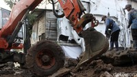Dua alat berat diterjunkan untuk mengangkat reruntuhan dinding yang menyumbang saluran Kali Setu.
