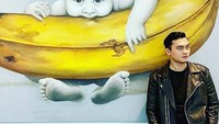 Berpose di depan lukisan pisang yang besar. Ikbal sukses membuat para penggemarnya di Instagram semakin ngefans. Foto: Instagram @ikbalfauzi_