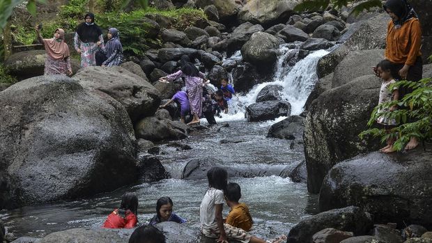 Pengunjung bermain di Sungai Cireong, Desa Sukaresik, Kecamatan Sindangkasih, Kabupaten Ciamis, Jawa Barat, Kamis (11/3/2021). Para pengunjung mengisi libur Isra Miraj dengan mengunjungi wisata alam Cireong yang dikelola Badan Usaha Milik Desa (BUMDes) dan Karang Taruna setempat, yang menyuguhkan daya tarik air sungai yang masih jernih dari kaki Gunung Sawal dan hamparan bebatuan besar. ANTARA FOTO/Adeng Bustomi/aww.