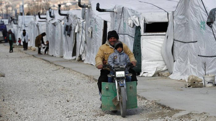 Nasib Pengungsi Suriah, Satu Dekade Tanpa Masa Depan A Syrian displaced man and his son ride a motorcycle, as they drive between the tents at a refugee camp, in Bar Elias, in eastern Lebanon's Bekaa valley, Friday, March 5, 2021. Syria has been mired in civil war since 2011, after Syrians rose up against President Bashar Assad amid a wave of Arab Spring uprisings. Nearly ten years later, millions of displaced Syrians unlikely to return in the foreseeable future, even as they face deteriorating living conditions abroad. The Syrian conflict has resulted in the largest displacement crisis since World War II. (AP Photo/Hussein Malla)