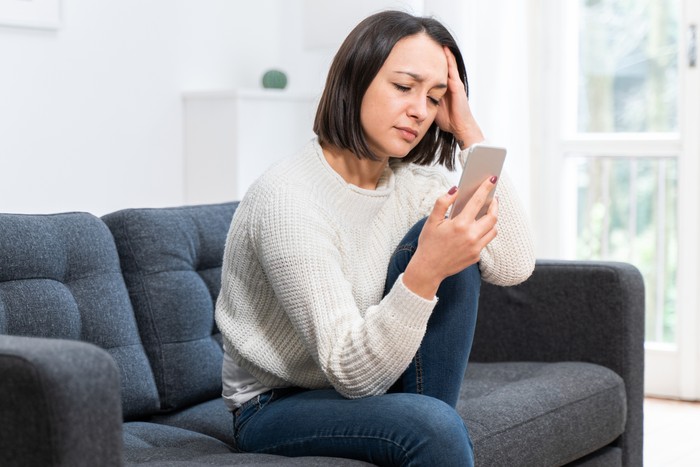 1217421659 One woman portrait holding phone at home