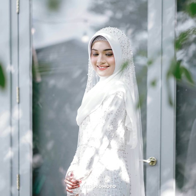 Di hari pernikahannya, Jihan tampak cantik mengenakan gaun putih panjang dan hijab berwarna senada. Penampilannya itu semakin terlihat menawan dengan ulasan makeup natural di wajahnya. Foto: Instagram/@thepotomoto