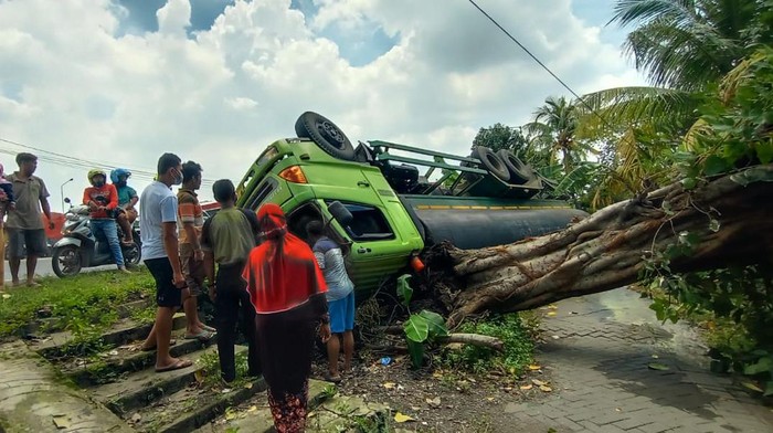 Truk tangki muat HCL yang diparkir di bahu jalan tiba-tiba terguling. Truk terguling karena bahu jalan tersebut ambles.