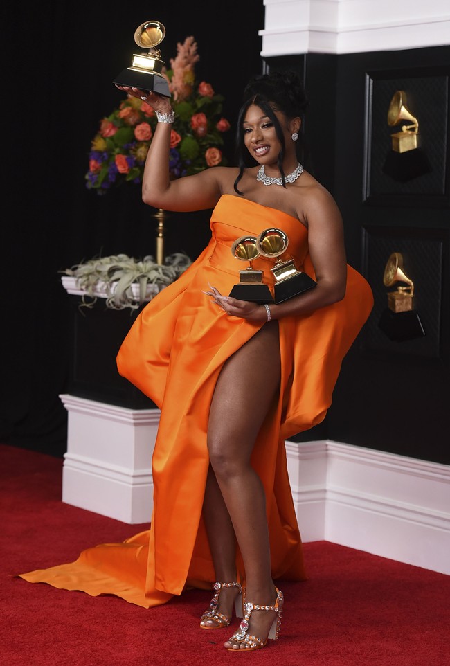 Megan Thee Stallion tampil fresh dalam balutan gaun strapless beraksen dramatis dari Dolce & Gabbana. Gaun berwarna oranye semakin membuat kulit cokelatnya terlihat segar. Foto: AP/Jordan Strauss