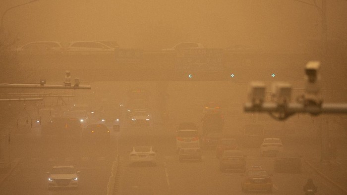 Gegara Badai Pasir, China Diselimuti Kabut Kuning Berbahaya Cars are driven along a street amid a sandstorm during the morning rush hour in Beijing, Monday, March 15, 2021. The sandstorm brought a tinted haze to Beijing's skies and sent air quality indices soaring on Monday. (AP Photo/Mark Schiefelbein)