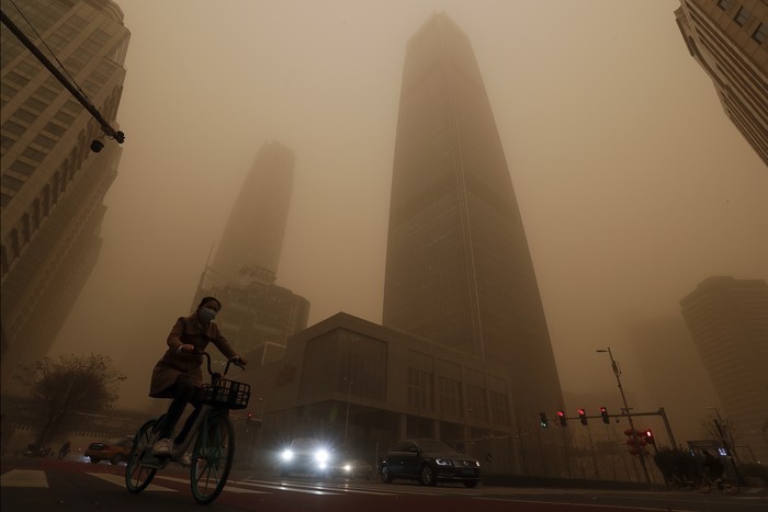 A cyclist and motorists move past office buildings amid a sandstorm during the morning rush hour in the central business district in Beijing, Monday, March 15, 2021. The sandstorm brought a tinted haze to Beijings skies and sent air quality indices soaring on Monday. (AP Photo/Andy Wong)