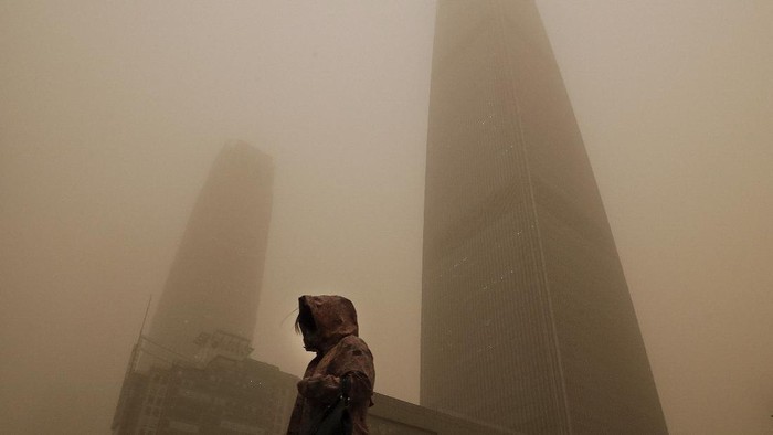 Gegara Badai Pasir, China Diselimuti Kabut Kuning Berbahaya A cyclist and motorists move past office buildings amid a sandstorm during the morning rush hour in the central business district in Beijing, Monday, March 15, 2021. The sandstorm brought a tinted haze to Beijing's skies and sent air quality indices soaring on Monday. (AP Photo/Andy Wong)