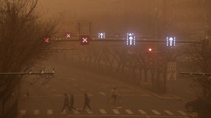 Gegara Badai Pasir, China Diselimuti Kabut Kuning Berbahaya A cyclist and motorists move past office buildings amid a sandstorm during the morning rush hour in the central business district in Beijing, Monday, March 15, 2021. The sandstorm brought a tinted haze to Beijing's skies and sent air quality indices soaring on Monday. (AP Photo/Andy Wong)