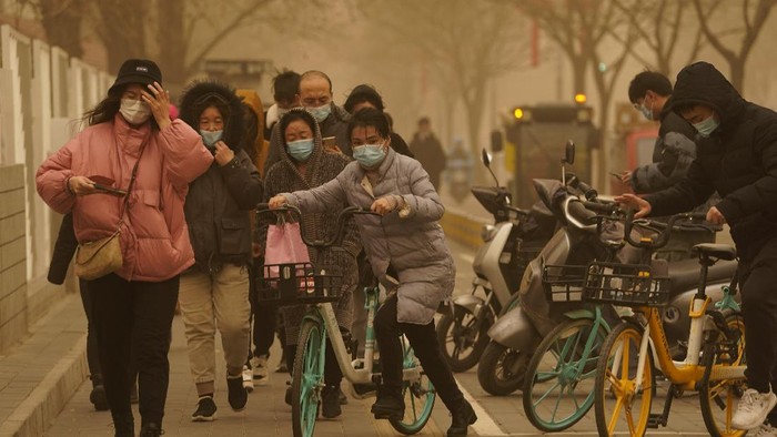 Gegara Badai Pasir, China Diselimuti Kabut Kuning Berbahaya A woman walks her dogs during a sandstorm in Beijing, Monday, March 15, 2021. The sandstorm brought a tinted haze to Beijing's skies and sent air quality indices soaring on Monday. (AP Photo/Ng Han Guan)