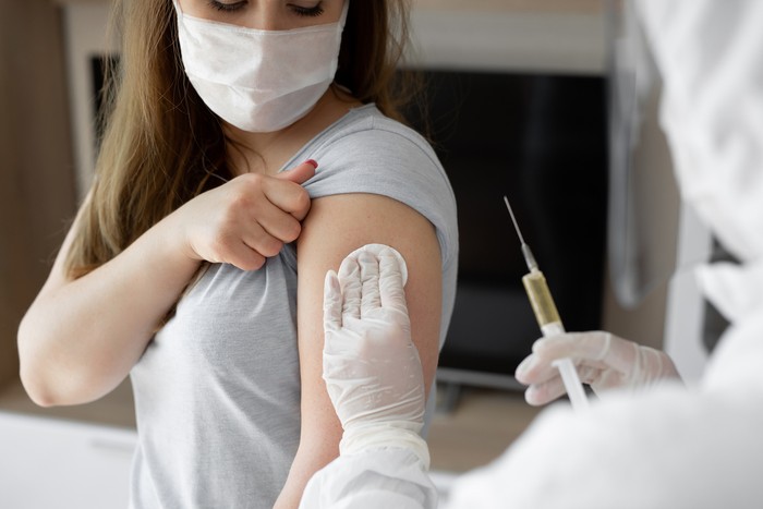 Ilustrasi vaksin Doctor in personal protective suit or PPE inject vaccine shot to stimulating immunity of woman patient at risk of coronavirus infection. Coronavirus,covid-19 and vaccination concept.