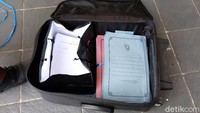 Berkas yang diamanan dimasukkan ke dalam koper hitam. 