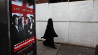 Seorang wanita muslim bebas yang mengenakan burqa  berjalan melalui jalan-jalan di kawasan Spark Hill Birmingham Januari 2010 di Birmingham, Inggris. Christopher Furlong/Getty Images.