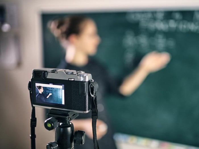 Young teacher teaching remotely using camera to stream lesson.