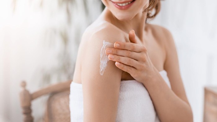 Dry Elbows Treatment. Smiling Black Woman Applying Moisturising Cream At Home, Healing Cracked Skin