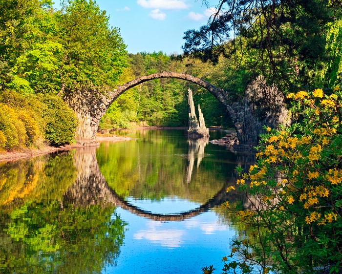 Spectacular autumn season in Azalea and Rhododendron Park Kromlau. Rakotz Bridge, Rakotzbrucke Devils Bridge in Kromlau, Saxony, Germany. Horizontal outdoor colorful image