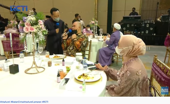 Mulan Jameela duduk berdekatan dengan suaminya Ahmad Dhani yang juga hadir di lamaran Aurel dan Atta. Dhani tampak memakai batik lengan panjang, sedangkan Mulan mengenakan dress cantik berwarna pink. Foto: Dok. YouTube RCTI - ENTERTAINMENT