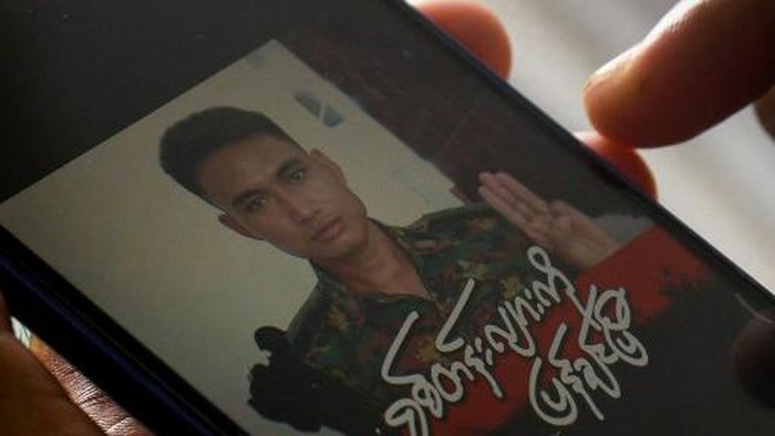 This screengrab provided via AFPTV and taken on March 14, 2021 shows Shing Ling, a former Myanmar soldier who deserted the military to join the democracy movement in the aftermath of the military coup, looking at his Facebook profile showing his picture wearing a military uniform and holding up the three finger salute in Yangon. - Despite feeling 