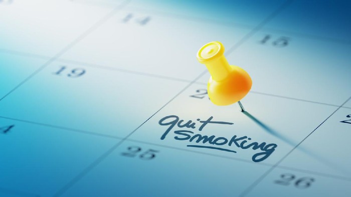 Ilustrasi berhenti merokok Concept image of a Calendar with a yellow push pin. Closeup shot of a thumbtack attached. The words Quit Smoking written on a white notebook to remind you an important appointment.