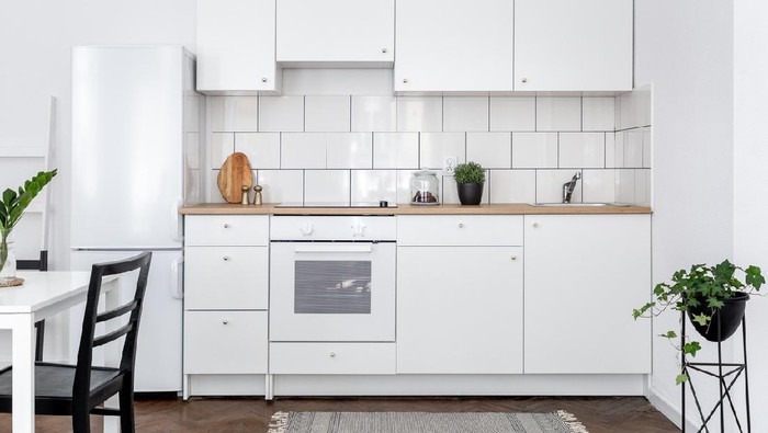 Contemporary kitchen with white cupboards and dining table with black chairs